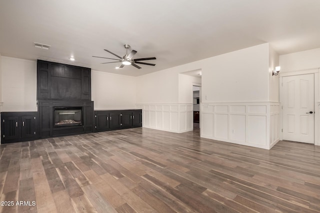 unfurnished living room with visible vents, a fireplace, a ceiling fan, and wood finished floors