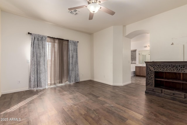 living area featuring arched walkways, visible vents, a ceiling fan, baseboards, and dark wood finished floors