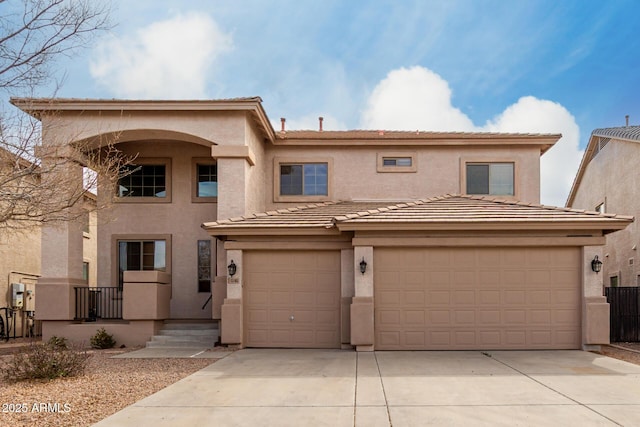 view of front of property featuring driveway, a tiled roof, a garage, and stucco siding