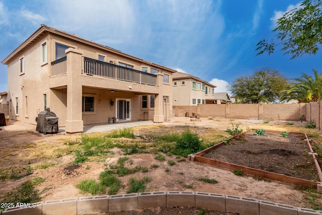 rear view of property featuring stucco siding, a fenced backyard, a vegetable garden, and a patio