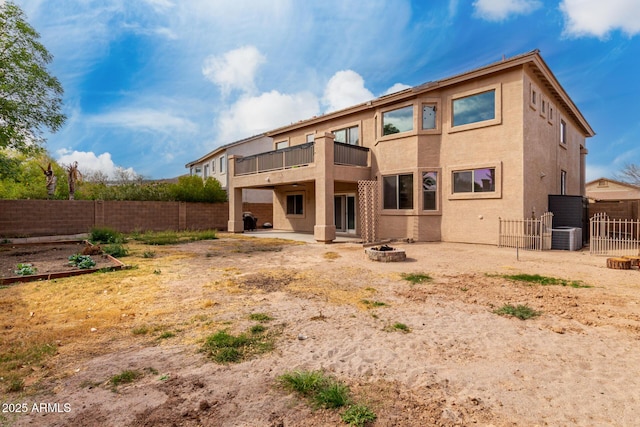 rear view of house featuring a patio, stucco siding, a balcony, a fenced backyard, and a fire pit