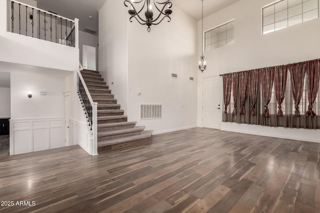 foyer with stairs, wood finished floors, visible vents, and a notable chandelier