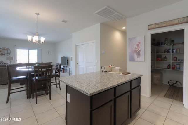 kitchen featuring light stone counters, light tile patterned floors, dark brown cabinets, decorative light fixtures, and a notable chandelier