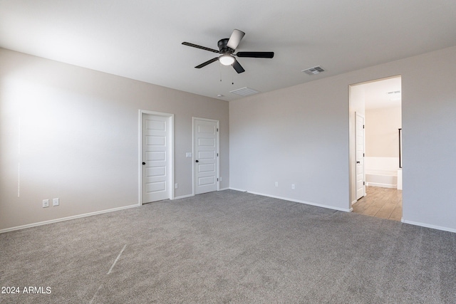 unfurnished bedroom with connected bathroom, two closets, light carpet, and ceiling fan