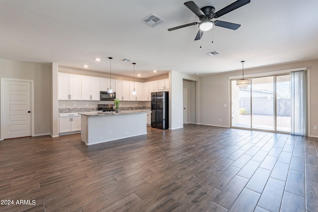 kitchen featuring appliances with stainless steel finishes, white cabinetry, dark wood-type flooring, a kitchen island, and decorative light fixtures