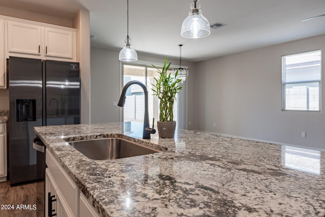 kitchen featuring white cabinets, light stone counters, sink, and stainless steel fridge