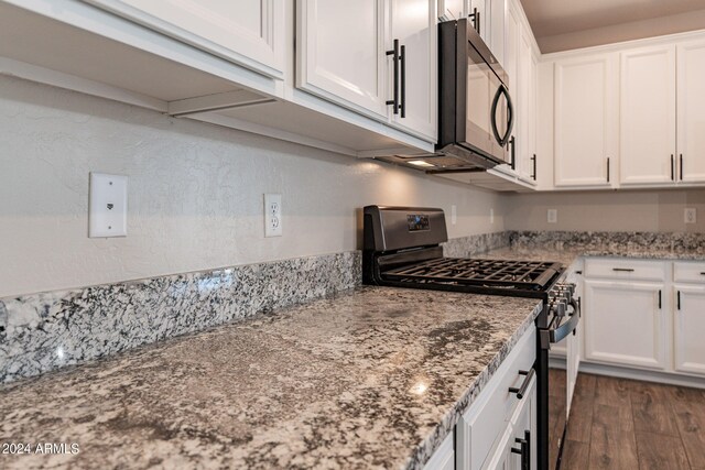 kitchen featuring light stone countertops, stainless steel gas stove, dark hardwood / wood-style flooring, and white cabinetry