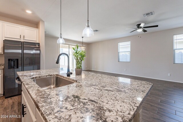 kitchen featuring dark hardwood / wood-style floors, stainless steel fridge, a center island with sink, and sink