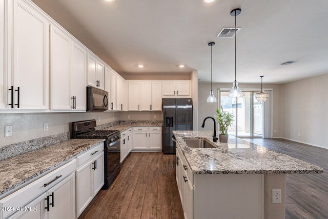 kitchen with sink, an island with sink, white cabinetry, black appliances, and dark hardwood / wood-style flooring