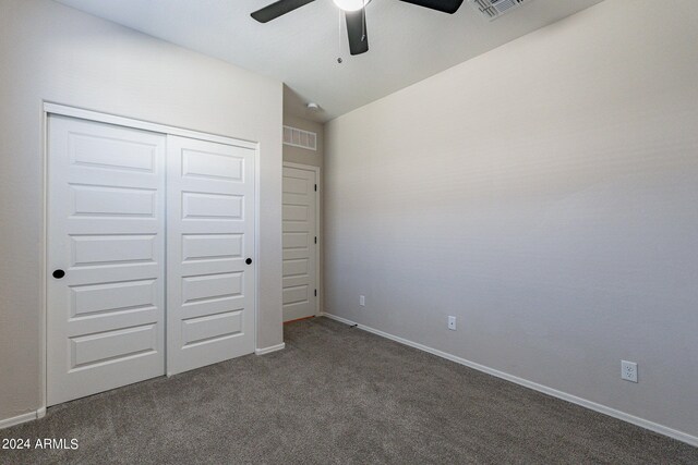 unfurnished bedroom featuring lofted ceiling, a closet, dark colored carpet, and ceiling fan