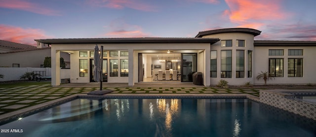 back house at dusk with a pool with hot tub and a patio area