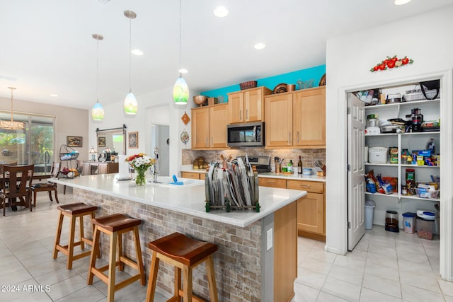 kitchen featuring a barn door, a breakfast bar, hanging light fixtures, and light brown cabinets