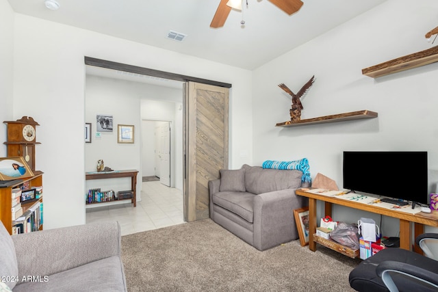 carpeted living room featuring a barn door and ceiling fan