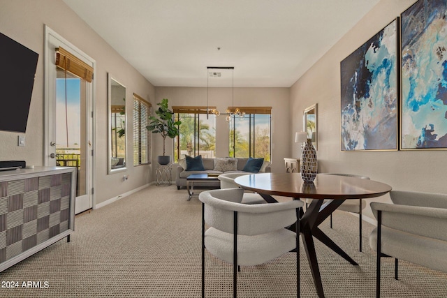 dining area with baseboards, a notable chandelier, and light colored carpet