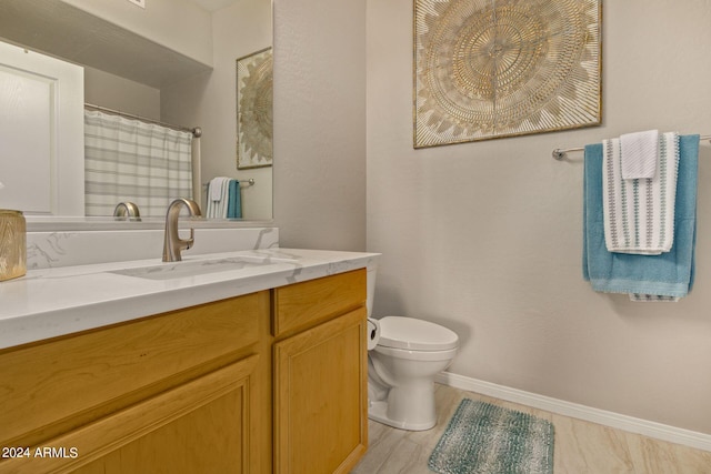 bathroom featuring toilet, vanity, and baseboards