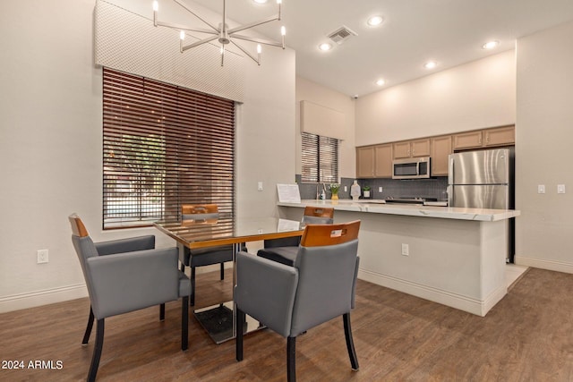 dining area with a high ceiling, wood finished floors, visible vents, and a notable chandelier