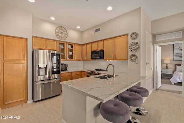 kitchen featuring a breakfast bar, visible vents, appliances with stainless steel finishes, glass insert cabinets, and a peninsula