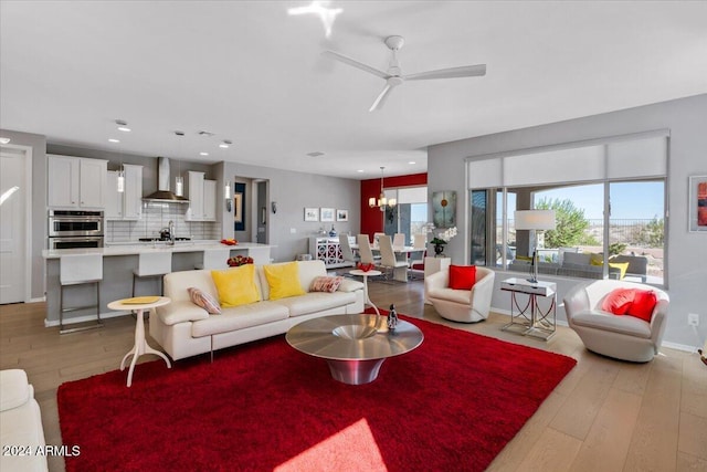 living room with ceiling fan with notable chandelier and light wood-type flooring