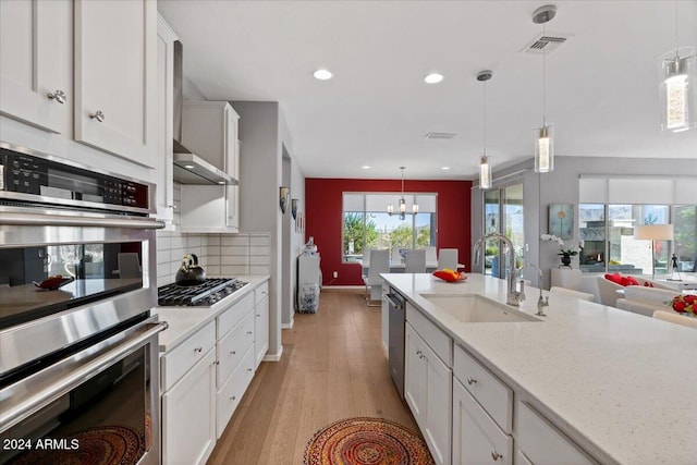 kitchen featuring light hardwood / wood-style floors, white cabinets, hanging light fixtures, sink, and appliances with stainless steel finishes