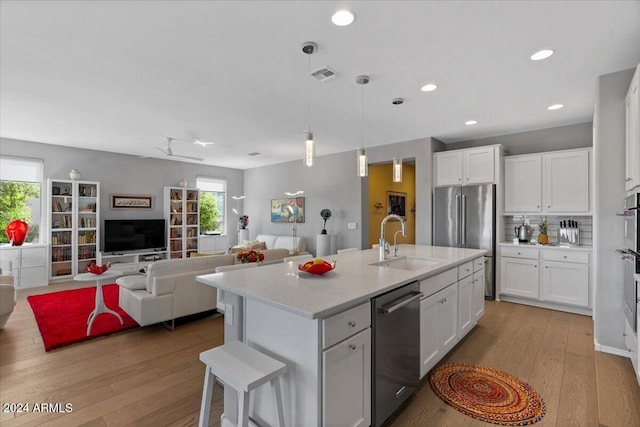 kitchen featuring white cabinetry, appliances with stainless steel finishes, an island with sink, and light wood-type flooring