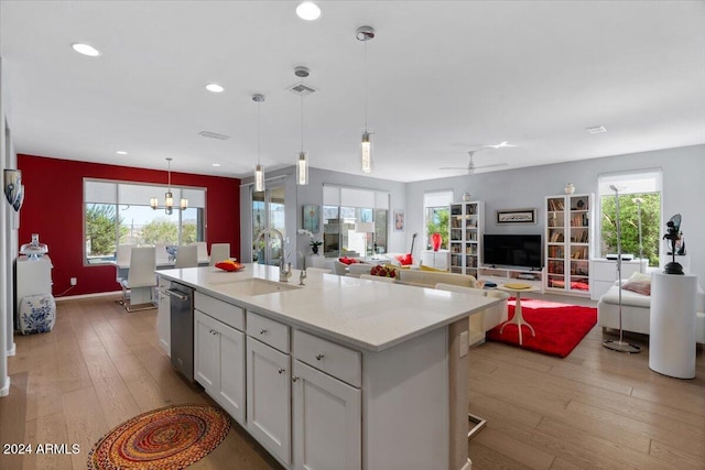 kitchen with white cabinets, a center island with sink, a healthy amount of sunlight, and pendant lighting