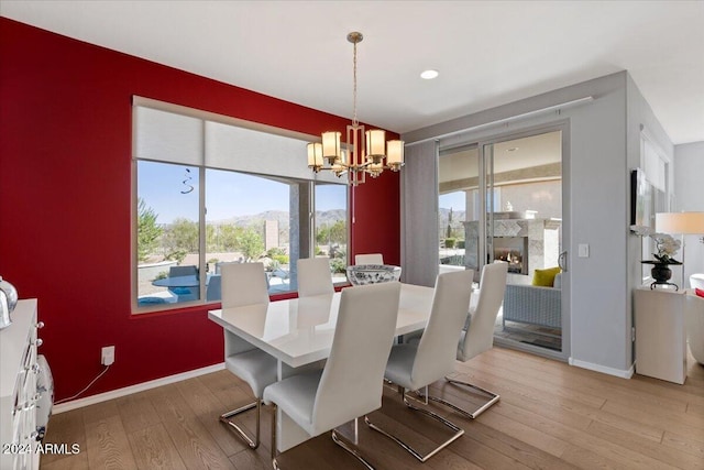 dining room featuring a mountain view, light hardwood / wood-style flooring, a high end fireplace, and an inviting chandelier