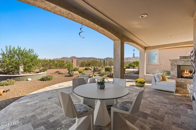 view of patio with a mountain view and an outdoor fireplace