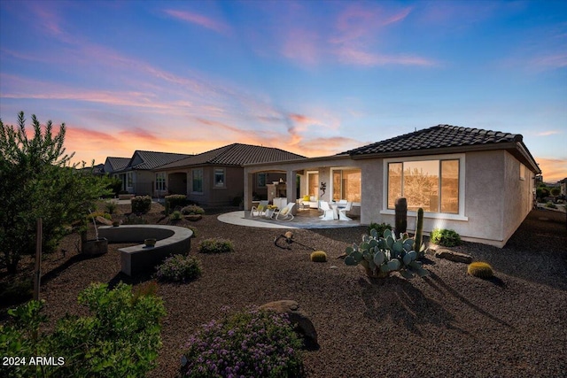 back house at dusk with a patio