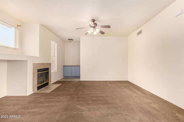 unfurnished living room with carpet flooring, ceiling fan, and a tiled fireplace