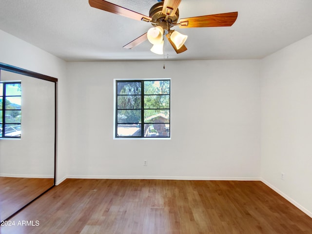 unfurnished bedroom with ceiling fan, a closet, wood finished floors, and baseboards