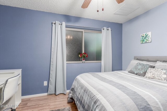 bedroom with wood finished floors, visible vents, baseboards, ceiling fan, and a textured ceiling