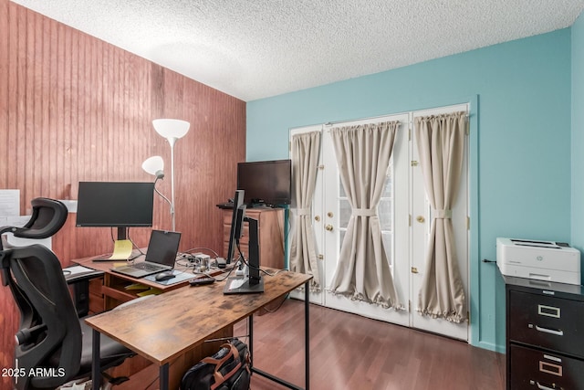 office space featuring a textured ceiling, wood finished floors, and wood walls