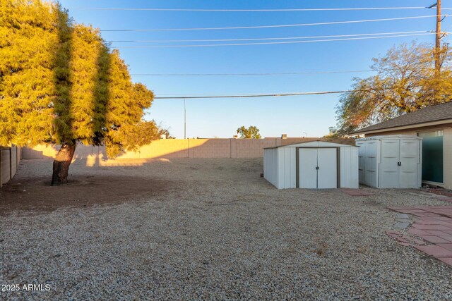 view of yard featuring a storage shed, a fenced backyard, and an outdoor structure