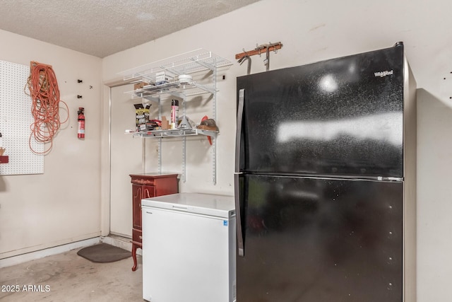 kitchen with white fridge, unfinished concrete flooring, a textured ceiling, and freestanding refrigerator