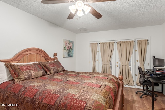 bedroom with a textured ceiling, ceiling fan, and wood finished floors