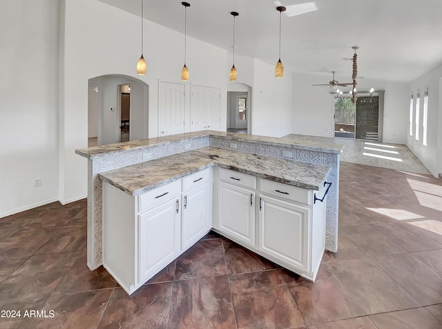 kitchen featuring white cabinets, pendant lighting, a chandelier, a center island, and light stone countertops