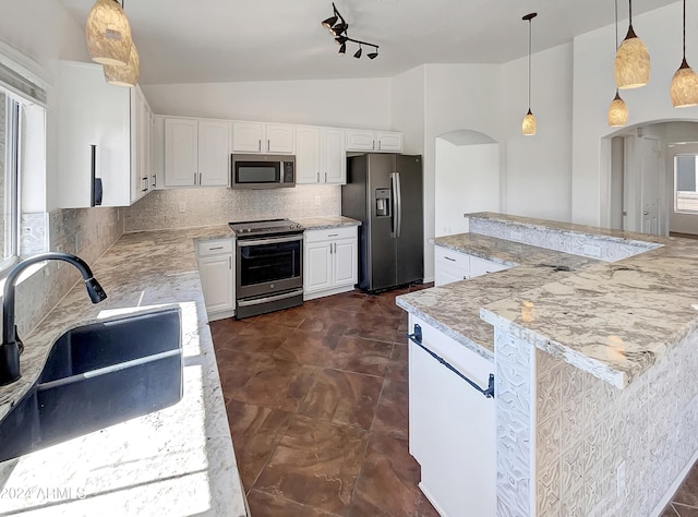 kitchen with white cabinets, light stone countertops, stainless steel appliances, decorative light fixtures, and sink