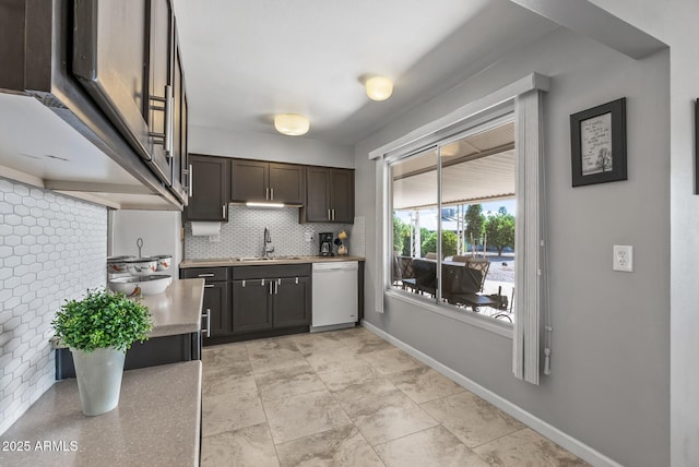 kitchen with light countertops, decorative backsplash, a sink, dishwasher, and baseboards