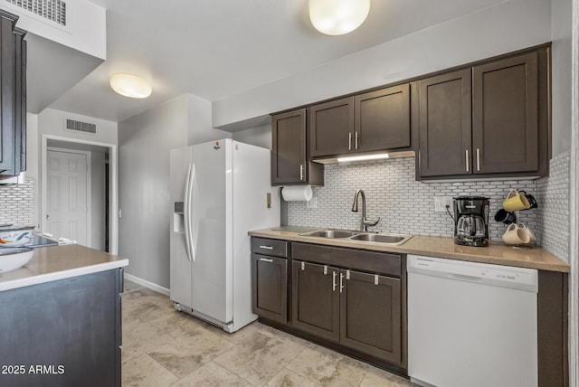 kitchen featuring dark brown cabinetry, white appliances, visible vents, light countertops, and a sink