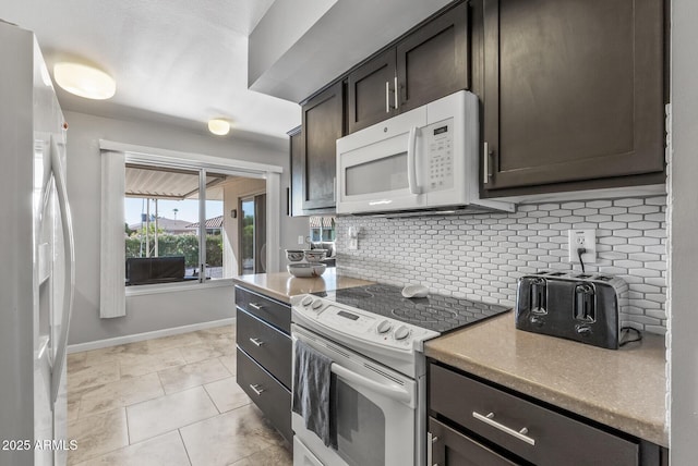 kitchen with dark brown cabinetry, white appliances, light tile patterned floors, baseboards, and backsplash