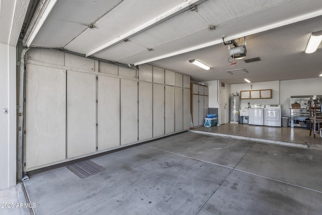 garage featuring visible vents, washer and dryer, and electric water heater