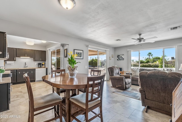 dining space with a textured ceiling, ceiling fan, and visible vents