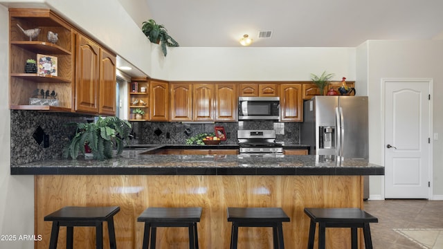 kitchen featuring stainless steel appliances, kitchen peninsula, a breakfast bar area, and backsplash