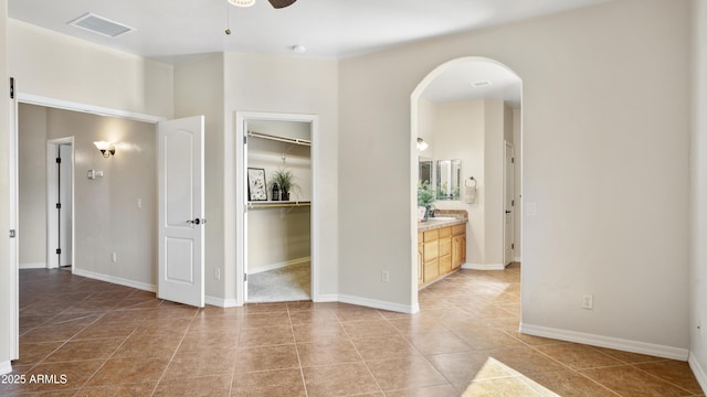 tiled empty room featuring ceiling fan and sink