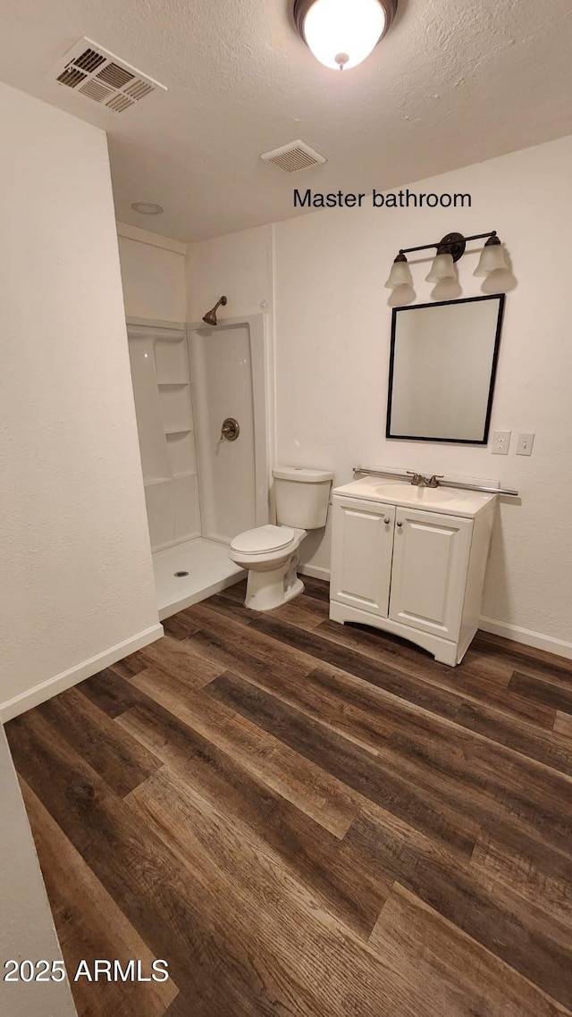 bathroom with toilet, wood-type flooring, a shower, and a textured ceiling