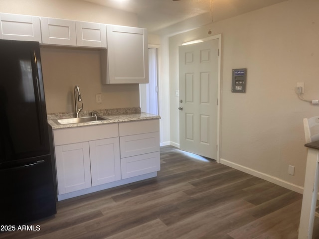 kitchen featuring dark hardwood / wood-style flooring, white cabinets, black refrigerator, and sink