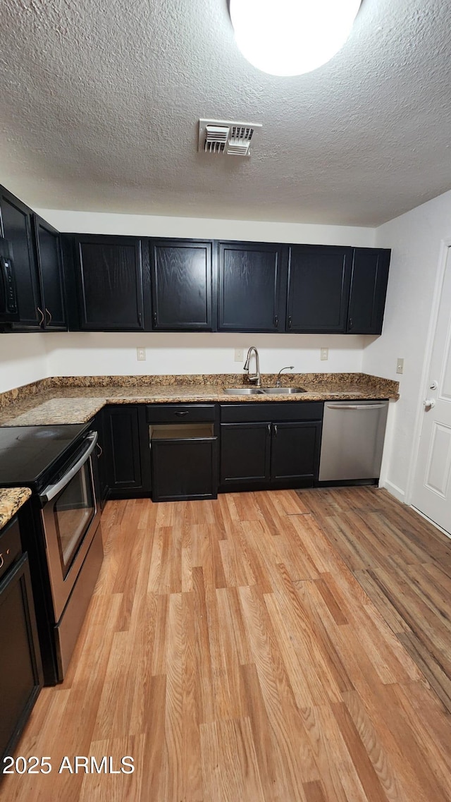 kitchen featuring stainless steel appliances, a textured ceiling, sink, and light wood-type flooring