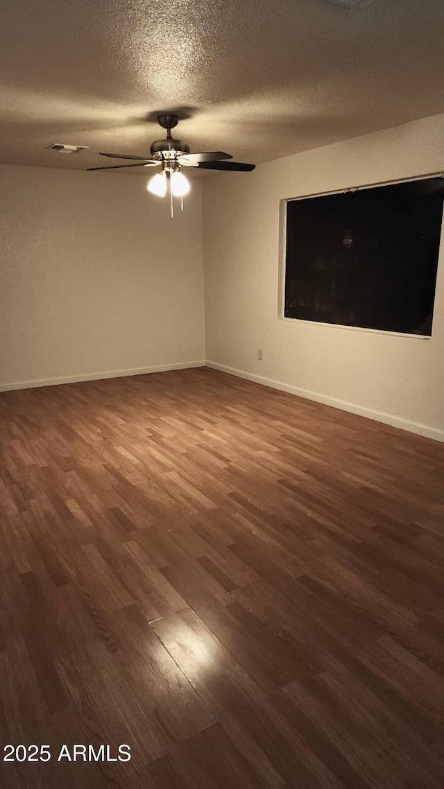 unfurnished room with a textured ceiling and dark hardwood / wood-style floors