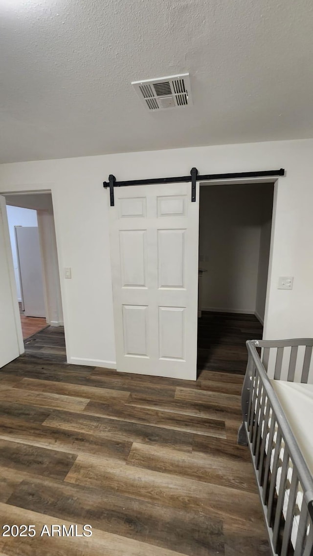 interior space featuring a textured ceiling, dark wood-type flooring, and a barn door