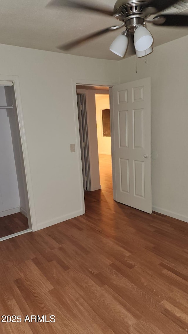 unfurnished bedroom featuring ceiling fan, a closet, and wood-type flooring